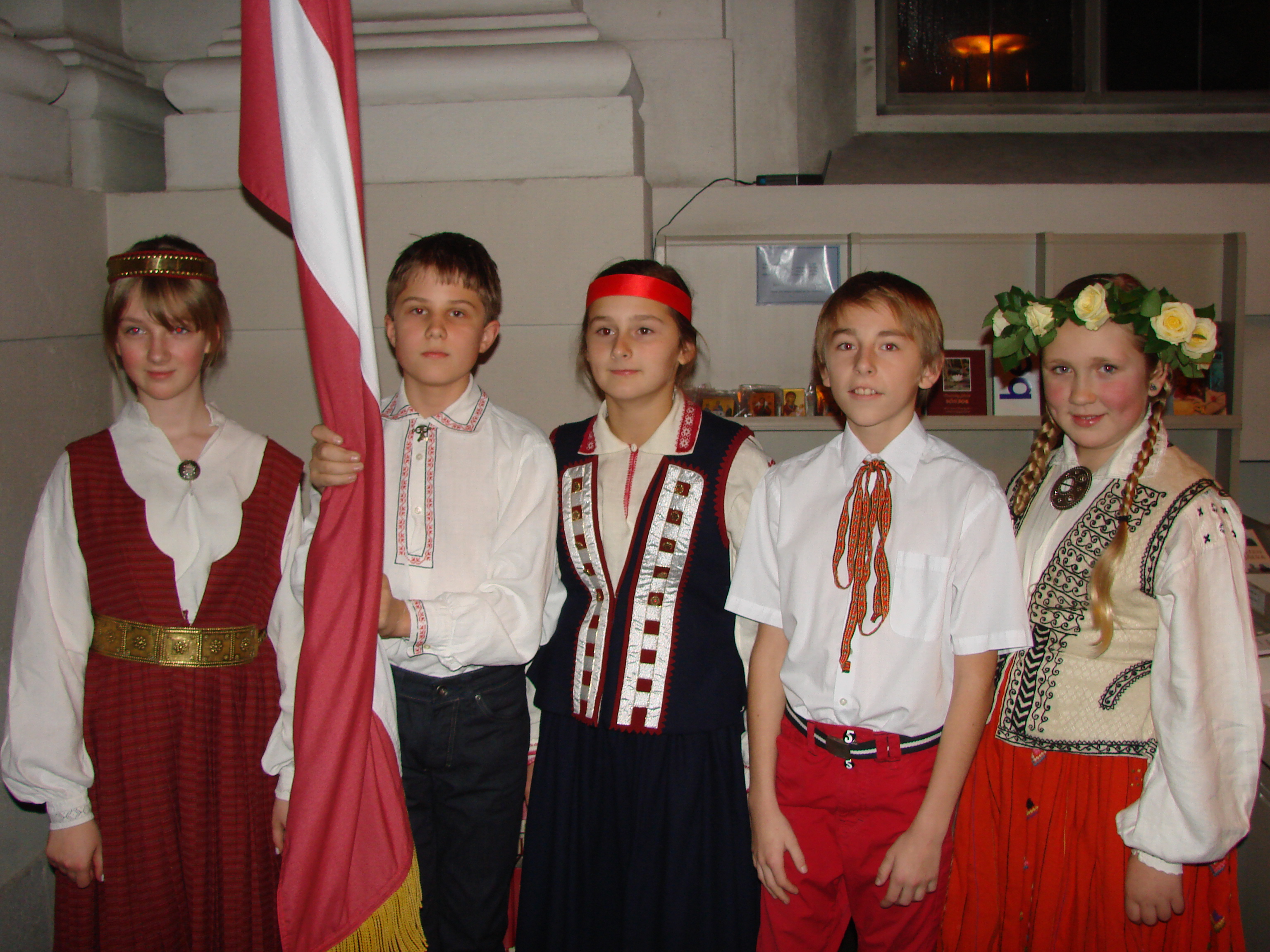 Skolas jaunieši Latvijas karoga priekšā
